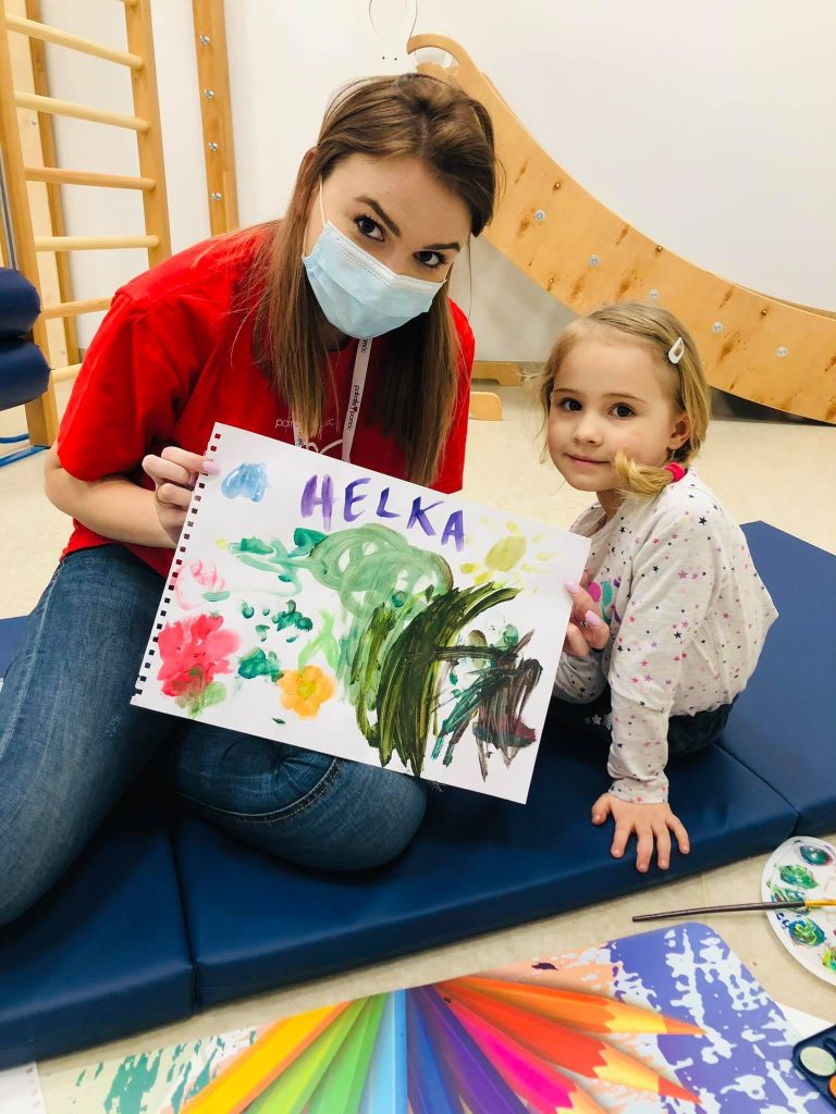 wolontariusz z dzieckiem pokazują namalowany farbami rysunek