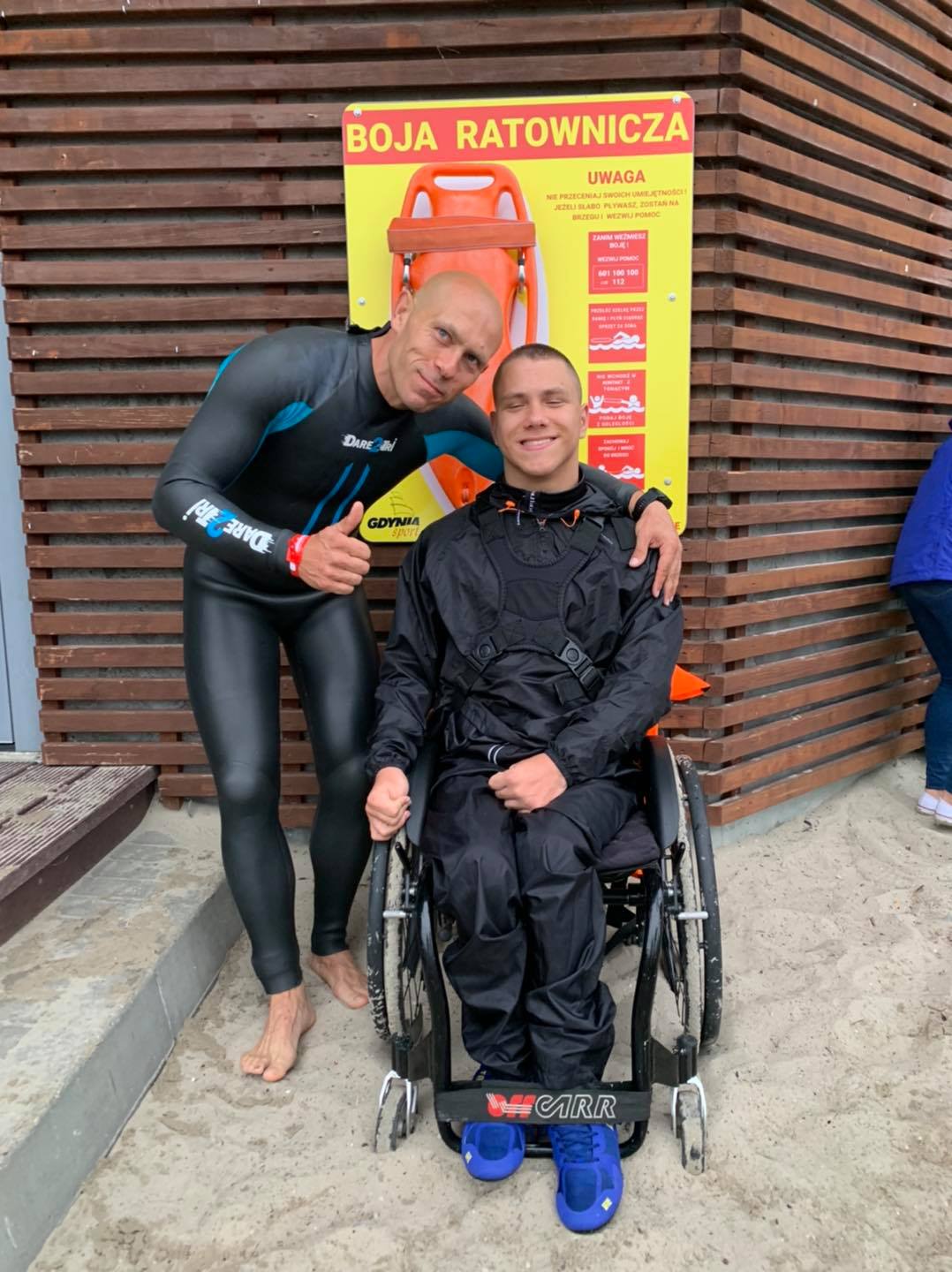 Jakub Jurczak na wózku inwalidzkim obok mężczyzna w stroju do pływania