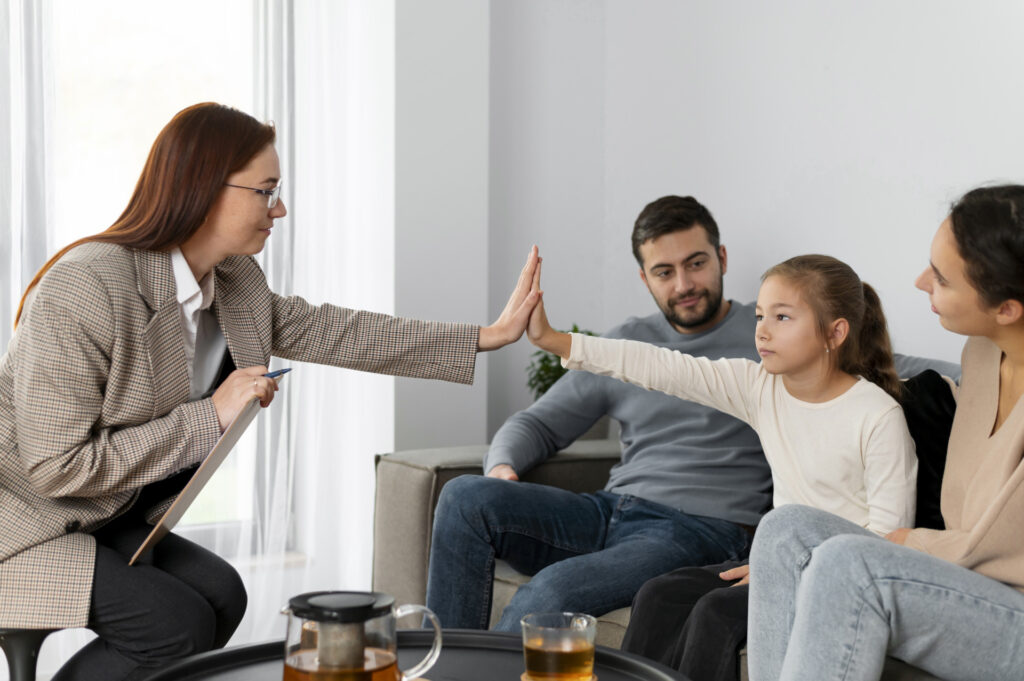 Rodzina podczas terapii, terapeuta i dziecko przybijają tzw. piątkę